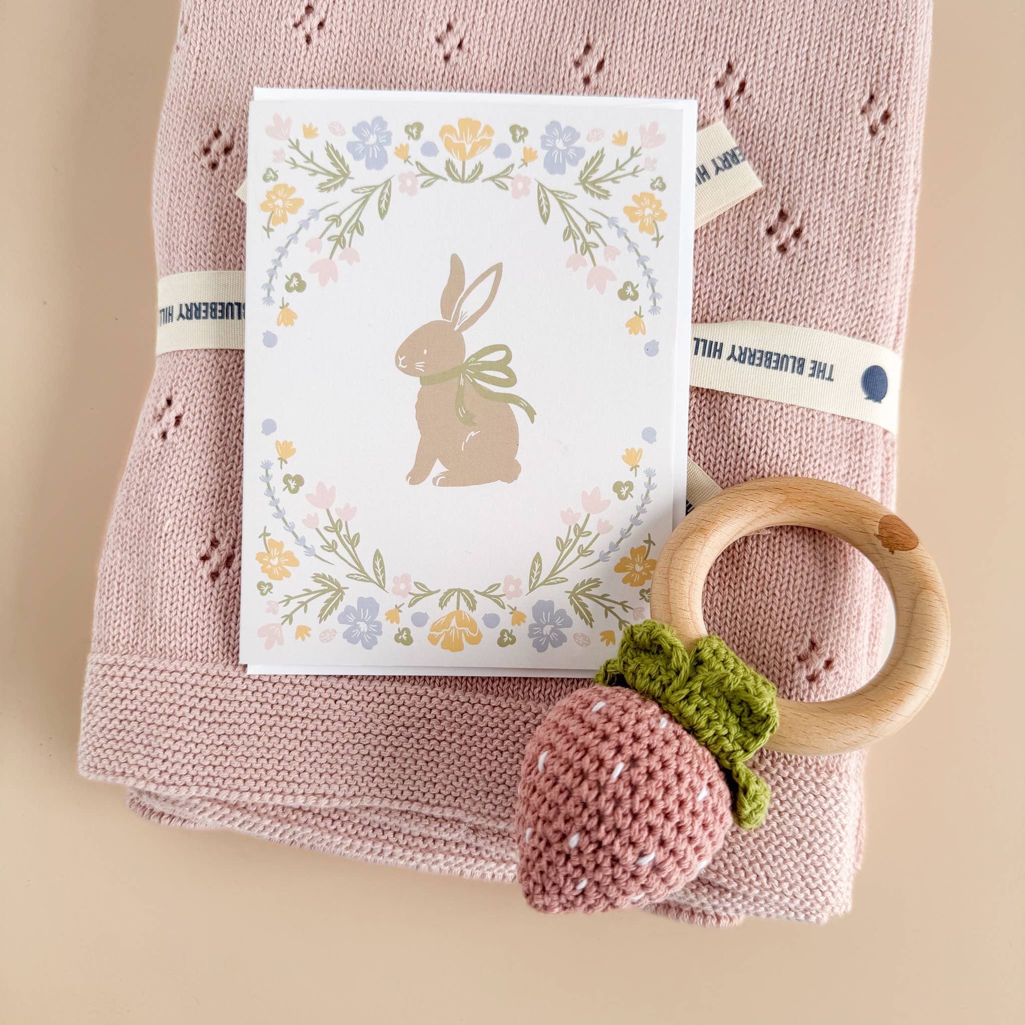 The Blueberry Hill Strawberry crochet teether on blush baby blanket with gift card