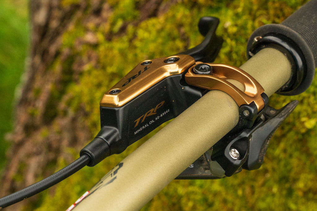 Close-up of a gold and black brake lever from TRP on a blurred natural background