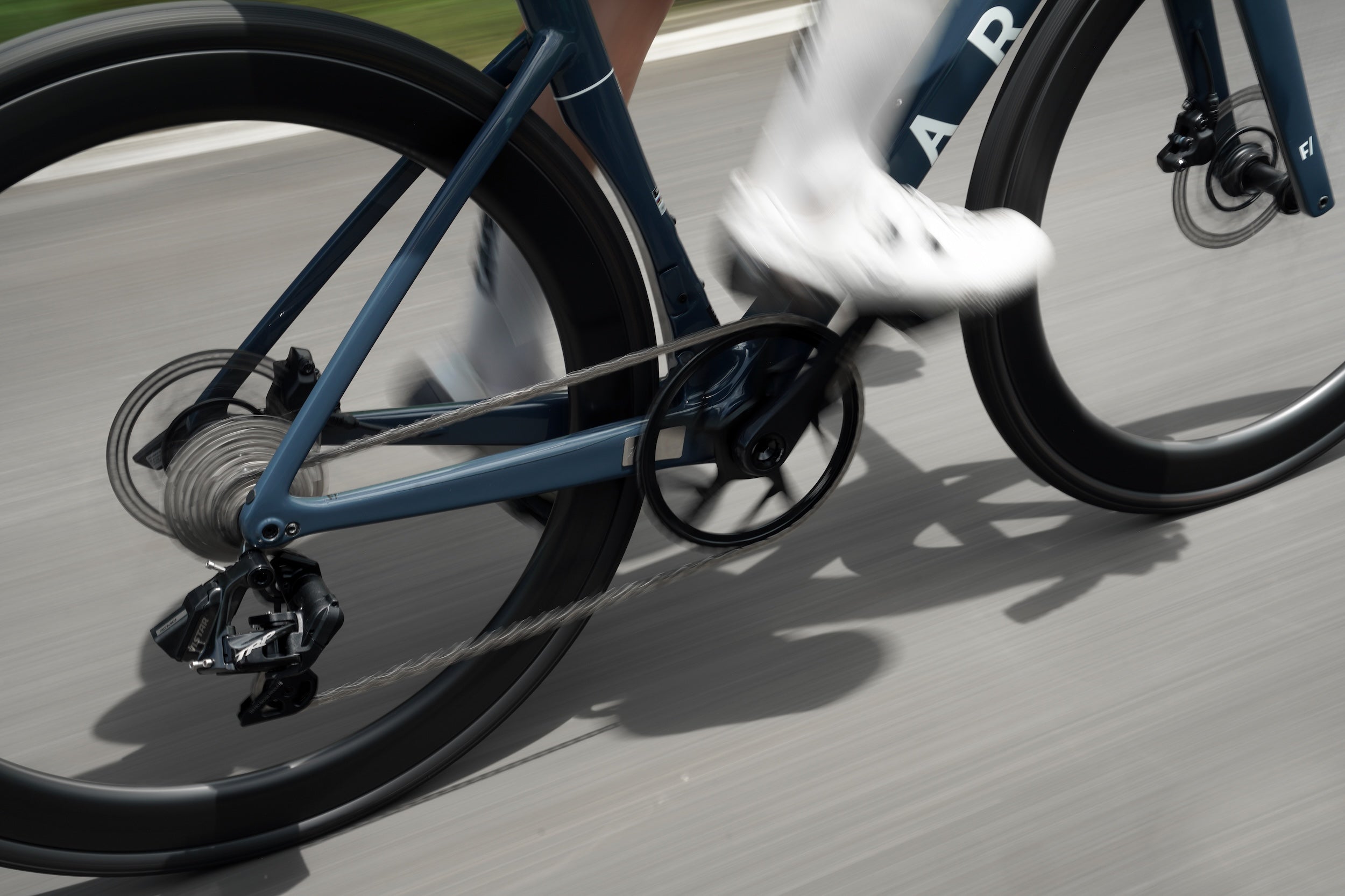 Close-up of a bicycle with the TRP VISTAR  and a person wearing white shoes on a road.