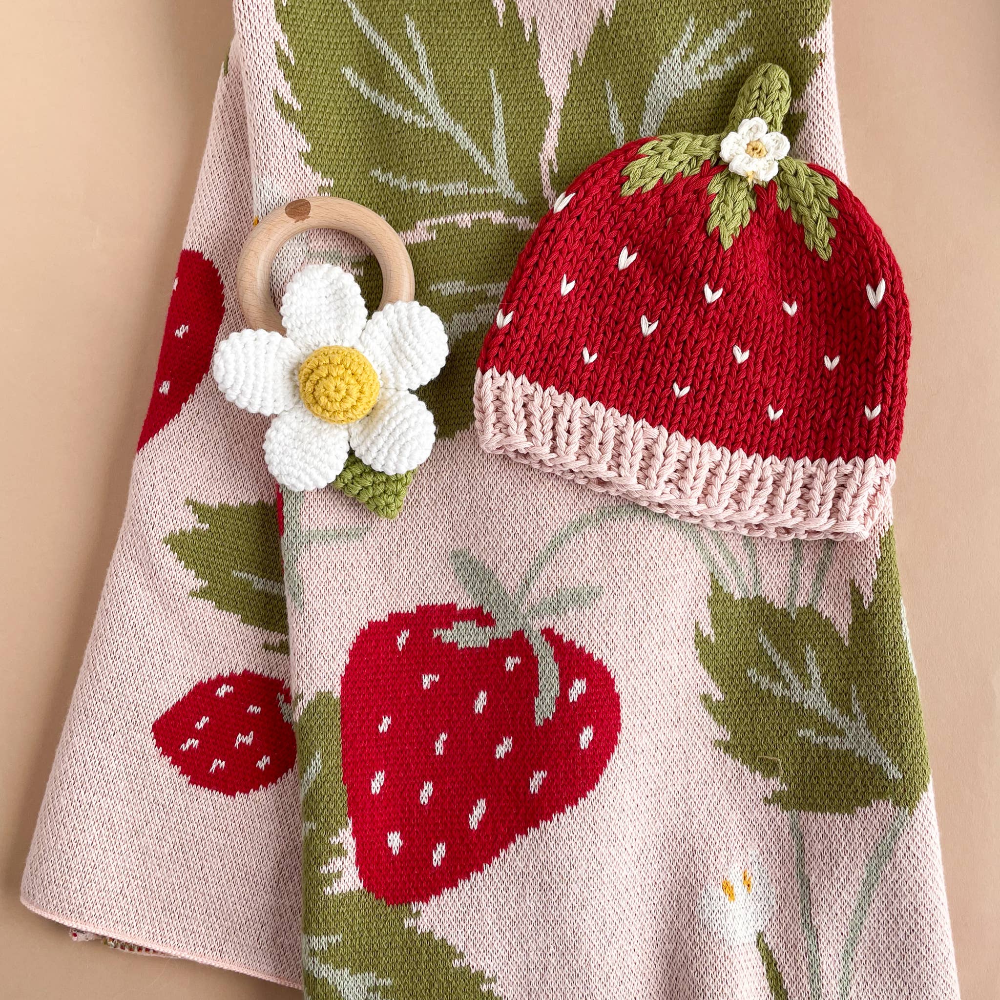 Strawberry knit baby hat and flower rattle on The Blueberry Hill Strawberry Bunny blanket